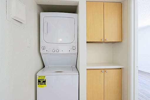 A white dishwasher is in a kitchen next to a wooden cabinet.