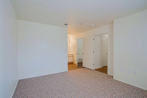 A large empty room with a carpeted floor and white walls.