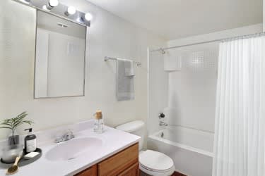 A white bathroom with a sink, toilet, and shower at Foothills Court Apartments, Phoenix, AZ 85029