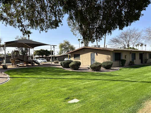 A grassy area in front of a building with a playground.