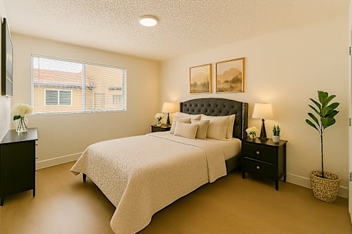 A bedroom with a large bed, nightstands, and a plant.