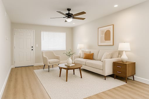 A living room with a white couch, a coffee table, and a ceiling fan.