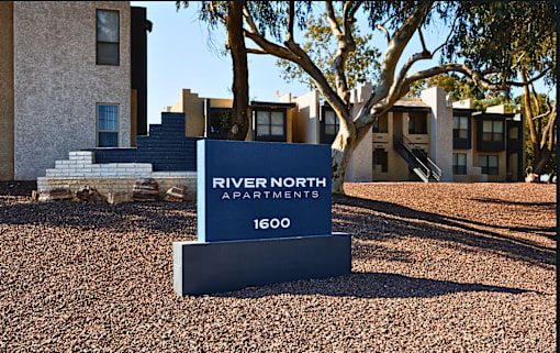 A sign for River North Apartments stands in front of a building.