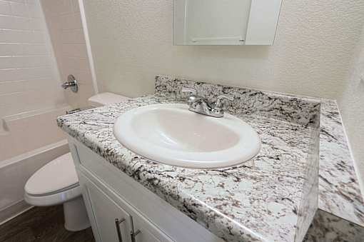 A white sink is on a marble countertop in a bathroom.