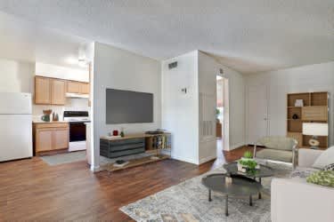 A living room with a couch, a coffee table, and a television at Foothills Court Apartments, Phoenix, AZ