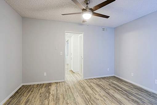 A room with a ceiling fan and wooden flooring.