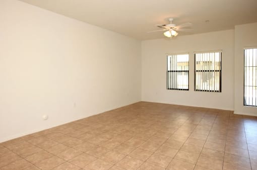 A room with a ceiling fan and two windows.
