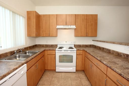 A kitchen with a stove, sink, and cabinets.