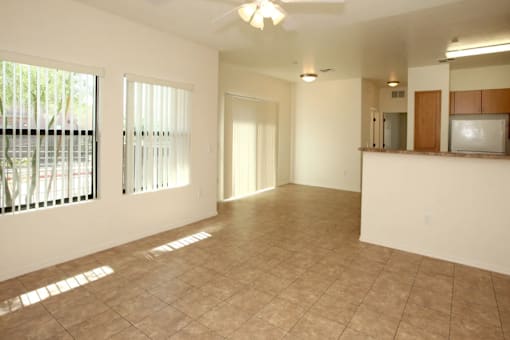 A spacious living room with a kitchenette in the background.