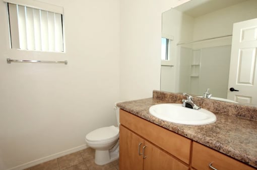A bathroom with a toilet, sink, and mirror.