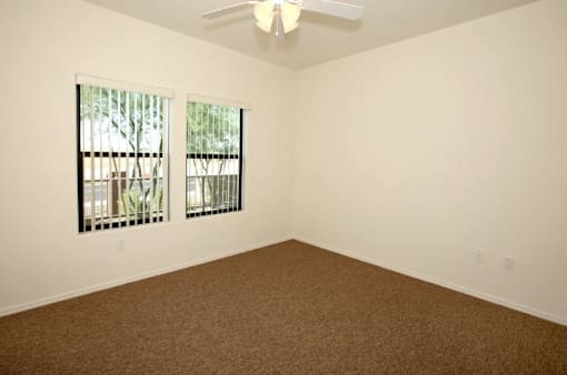 A room with a carpeted floor and a ceiling fan.