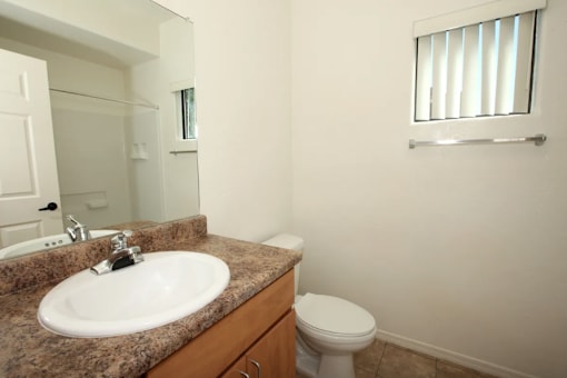 A bathroom with a toilet, sink and mirror.