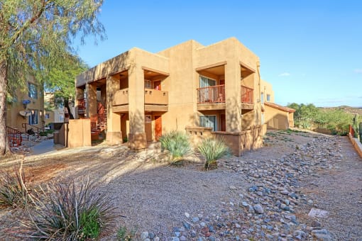 Apartment building exterior surrounded by gravel and vegetation.
