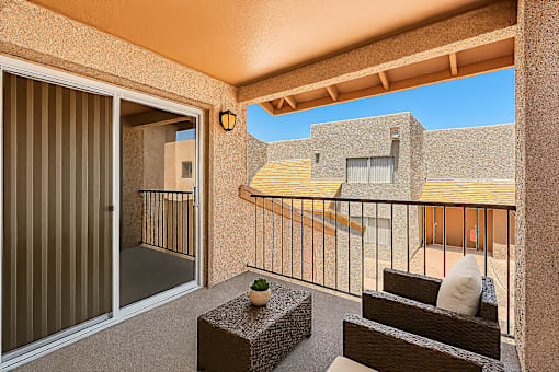 A balcony with a table and chairs overlooking a building.