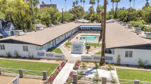 an aerial view of a white house with a pool and trees