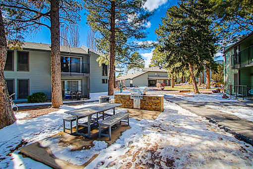 A snow-covered ground with a picnic table in the middle of a street.