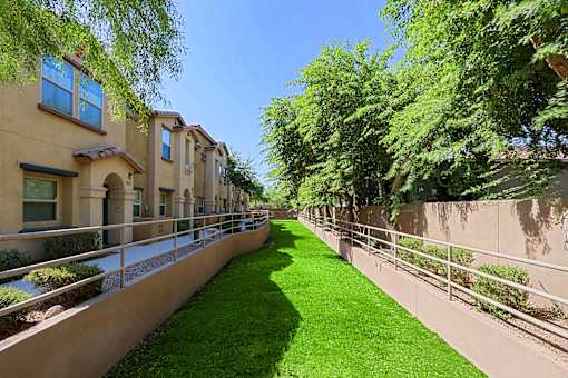 A row of houses with a green lawn in between.