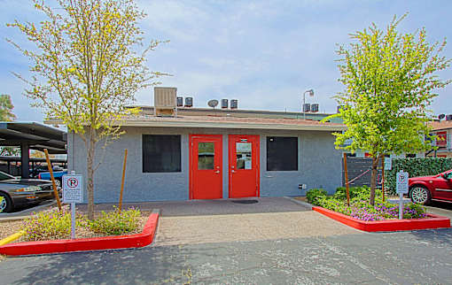 A building with a red door and a parking sign in front.