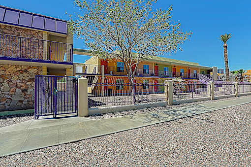 A building with a purple fence and a tree in front.