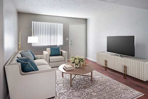 A living room with a white couch, a coffee table, and a flat screen TV at Gilbert Square Apartments, Mesa, AZ 85203
