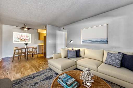 A living room with a beige couch, a coffee table, and a painting on the wall at Gilbert Square Apartments, Mesa, AZ 85203