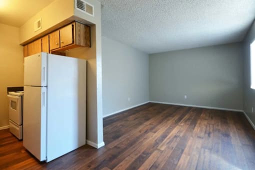 A white refrigerator is in a room with wood floors at Gilbert Square Apartments, Mesa