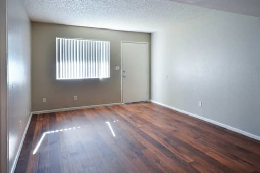 A room with wooden floors and a window with blinds at Gilbert Square Apartments, Mesa