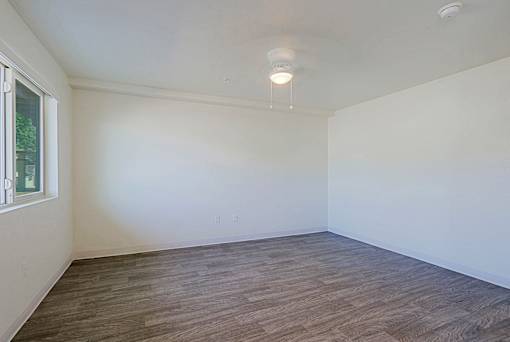 A room with wooden flooring and a window on the left side.