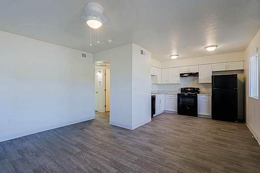 A kitchen with black appliances and wooden floors.