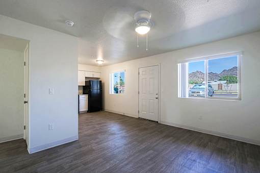 A room with a window showing a view of a house and mountains outside.