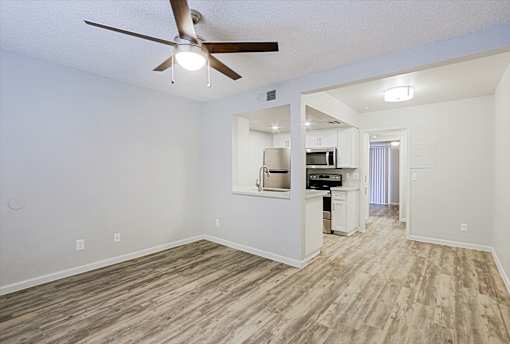 A room with a ceiling fan and a kitchenette.