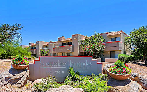 The Scottsdale Hacienda sign is in front of a building with a clear blue sky in the background.