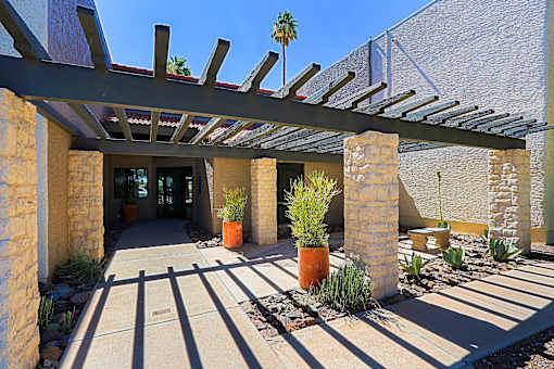 leasing office entrance: A patio with a pergola and potted plants.