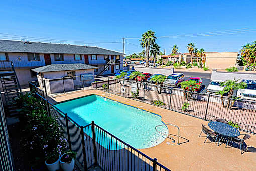 A pool surrounded by a black fence and chairs.