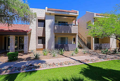 A modern house with a red tile roof and a stone wall.