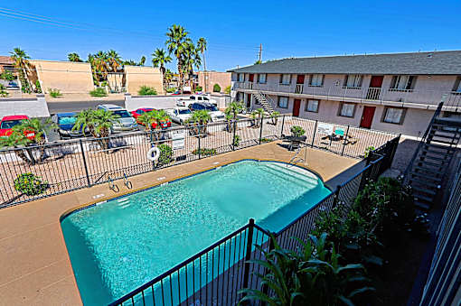 A pool surrounded by a fence and a building in the background.