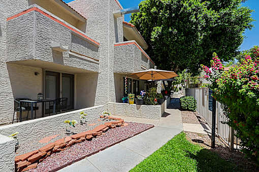 A building with a red roof and a patio with a table and chairs.