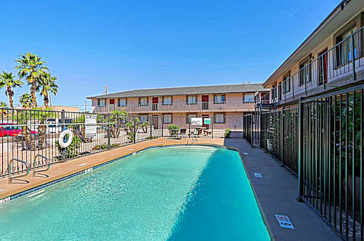 A swimming pool in front of a building with a fence around it.