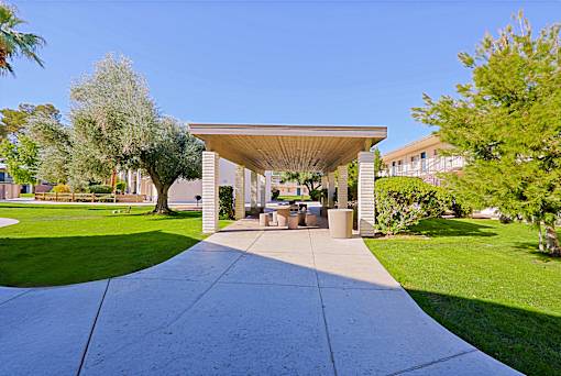 A pavement leads to a pavilion with a roof supported by four pillars.