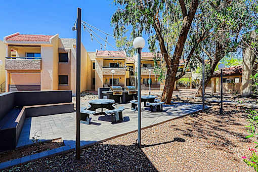 A sunny day at a modern outdoor seating area with picnic tables and benches.