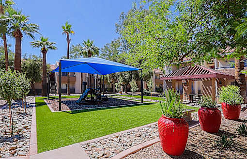 A patio area with a swing set and red vases.