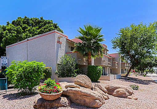 A house with a red roof and a palm tree in front.