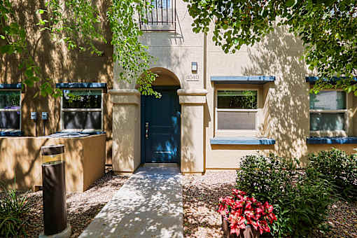 A building with a blue door and windows surrounded by greenery.