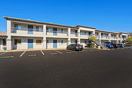 an apartment building with a parking lot and cars in front of it