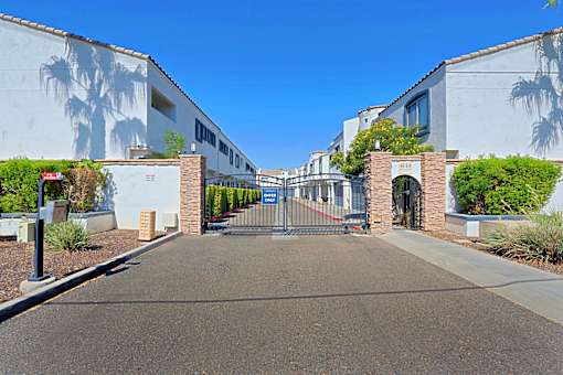 A gated entrance to a building with a wall mural of a palm tree.