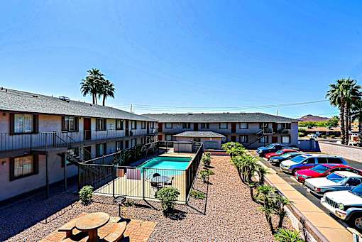 A sunny day at the apartment complex with a pool and palm trees.