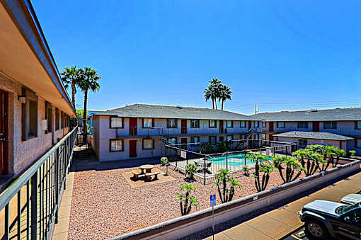 A sunny day at the apartment complex with a pool and palm trees.