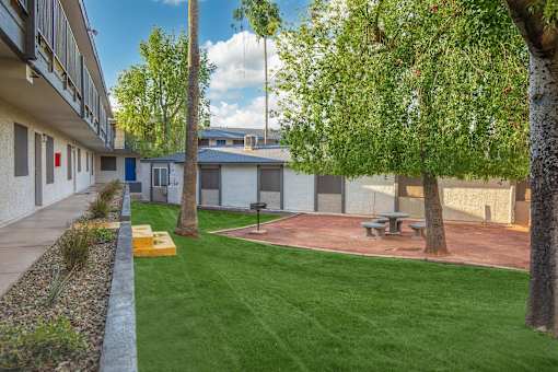A small grassy area with a picnic table and a tree in the foreground.