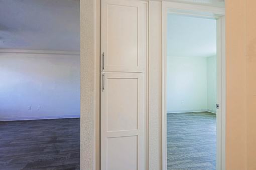 A white door is open to a room with a wooden floor.
