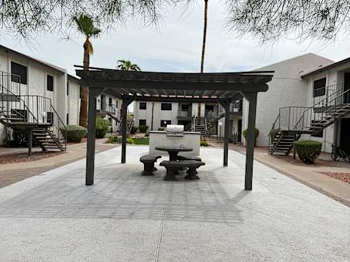 A patio with a table and chairs under a pergola.